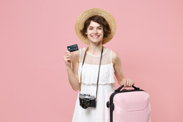 Smiling young tourist girl in summer dress hat with photo camera isolated on pink background....