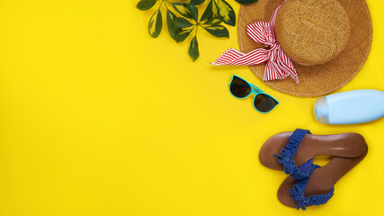Accessories for the beach season. Straw hat, sunglasses, sunblock and leaves sheflers isolated on a yellow background. Top view flat lay