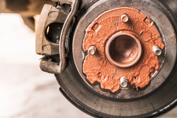 Old rusty worn brake discs are coated with copper grease in a passenger car. Car on a lift in a car...