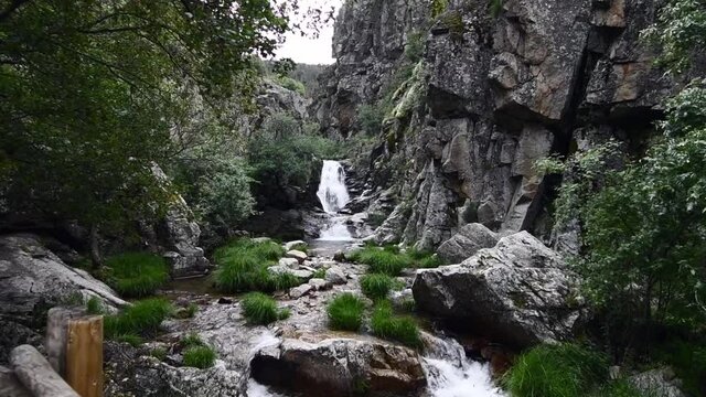 Small and beautiful waterfall in the middle of a very rocky area with lots of nature around in a natural park 