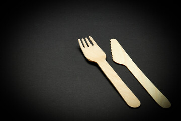 eco-friendly disposable utensils concept. close up bamboo or wooden cutlery over black color...