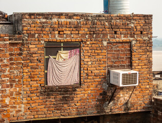 A brick wall of a house with an air conditioner attached.