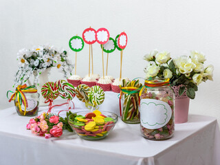 Sweet table standing on white background with sweets, lollipops, macaroni, marshmallows for children holiday or wedding.