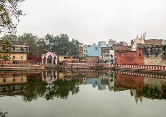 Obraz premium Ancient temples reflected in water of a tank in the city of Varanasi in India.