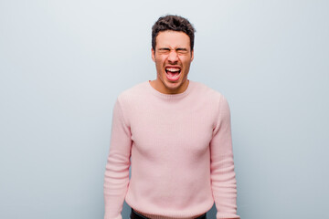 young arabian man shouting aggressively, looking very angry, frustrated, outraged or annoyed,...