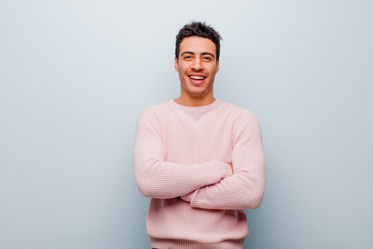 Young Arabian Man Looking Like A Happy, Proud And Satisfied Achiever Smiling With Arms Crossed Against Gray Wall