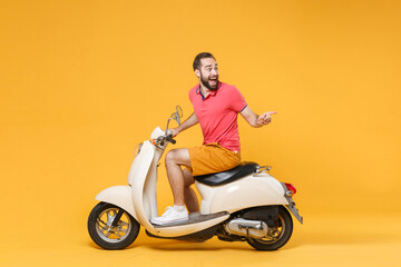 Side view of excited young bearded man guy in casual summer clothes driving moped isolated on...