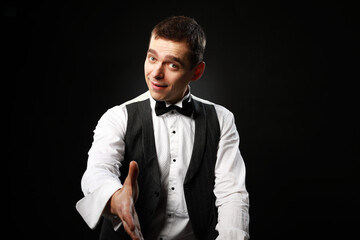 Portrait of a young and handsome man with emotion and funny face in black bow-tie isolated on black background.with copy space. 