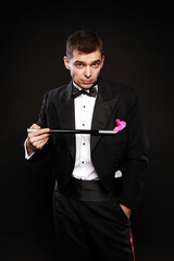 Obraz premium Funny magic man in tuxedo and bow tie with colorful handkerchief isolated on black background