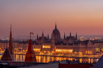 Hungary Parliament with lights on by Danube river in early morning before sunrise