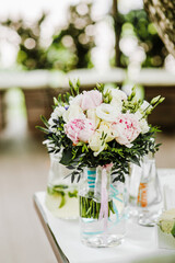Lovely white peony blooming flowers in glass vase on a white table. Floral composition, scene, daylight.
