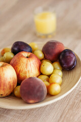 Delicious ripe juicy fruits and berries in a dish on the wooden table. A photo with a blurred background.