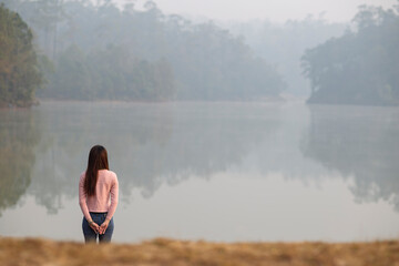 Fototapeta na wymiar young woman sitting on a lake shore