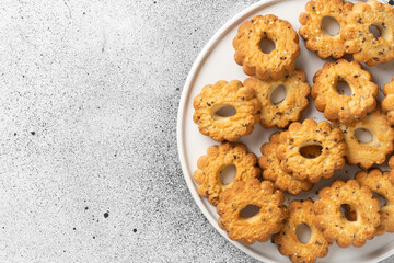 Shortbread in a large white ceramic plate on the light gray kitchen table. There are a lot of cookies in the plate. Homemade delicious pastries. Top view with a space for text