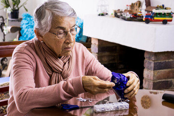 Senior woman at home arranging her prescription drugs into  weekly pill organizer