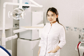 cheerful female dentist smiling in her office. dentistry student standing in a dental treatment room