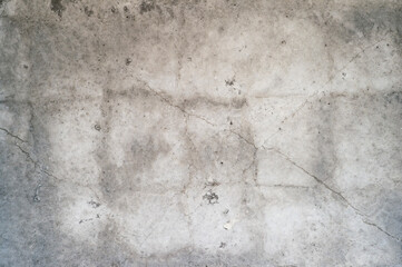 Grey concrete wall with cracks, rough surface and uneven color tone. Background