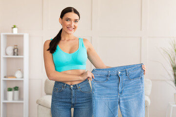 Woman Comparing Jeans After Weight Loss Standing At Home