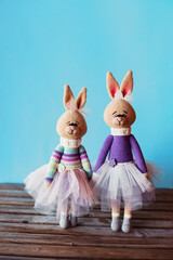Obraz premium Handmade knitted toys. Amigurumi bunnies in the beautiful dresses on the blue background. Crochet stuffed animals. Vertical