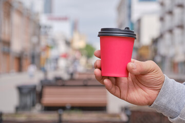 Mature man's hand holds red paper cup