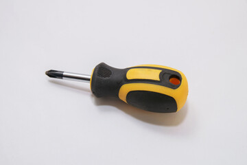 A small black and yellow screwdriver lies on a white background in the center