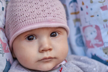 a baby in a pink cap with black eyes
