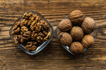 Whole and sheled walnut in a small plates on a vintage wooden table as a background. Walnuts is a healthy vegetarian protein nutritious food. Natural nuts snacks.