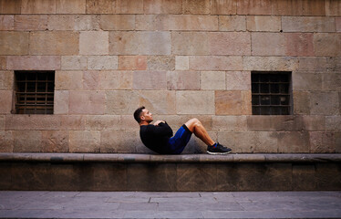Smiling young male jogger relaxing after intense exercising in the fresh air