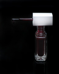 Fototapeta na wymiar Dark red coloured nail polish on a black background