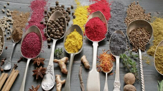 Spices on spoons with herbs on table dolly shot. Variety of seasonings cuisine concept