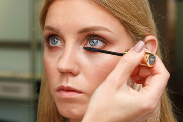 Makeup artist creates voluminous eyelashes of the model.