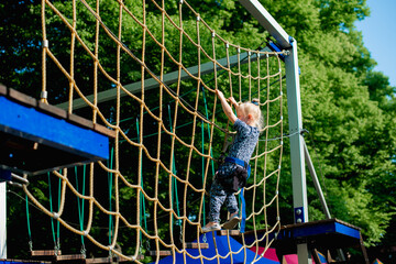 Girl kid enjoying activity in a climbing adventure park on a summer day. Childhood, lifestyle. 
