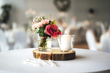 Elegant festive table setting with colorful flowers and candle on wooden stand. Wedding table decoration.