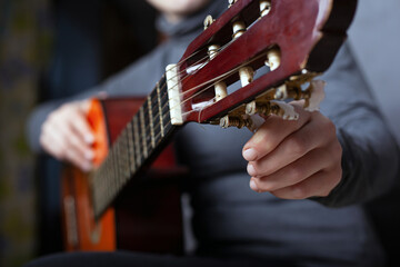 girl tunes an acoustic guitar close-up. playing a musical instrument.