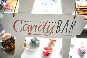 Candy bar lettering on white stand. Various sweets and gummy candies in background. Celebration,...