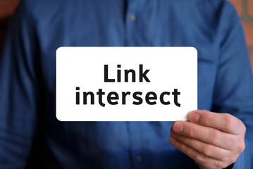 Link intersect - text on a white sign in the hand of a man in a blue shirt