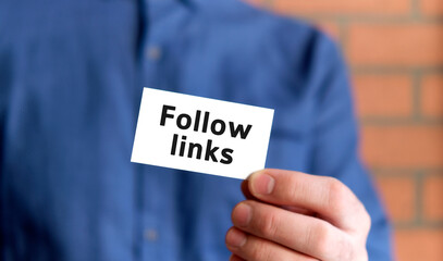 A man in a blue shirt holds a sign with the text of Follow links in one hand