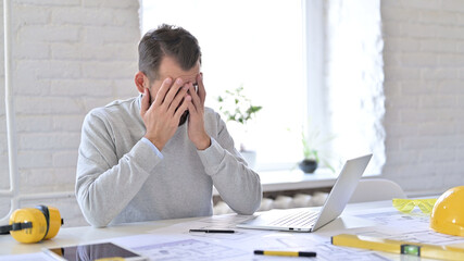 Frustrated Young Architect Covering Face with Hands at Work, Disappointed