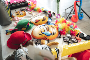Various party accessories laying on table. Emoji masks, hats, funny glasses, etc. Celebration,...