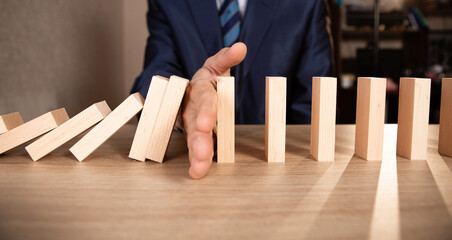 Close up hand Stopping Falling wooden Dominoes effect from continuous toppled or risk, strategy and...