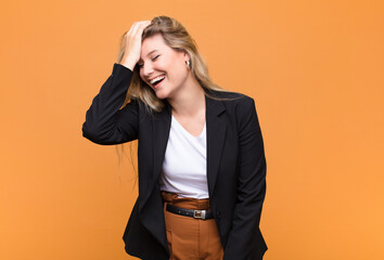young pretty latin woman laughing and slapping forehead like saying d‚Äôoh! I forgot or that...