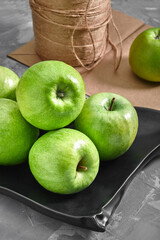 Green apples against gray background with a paper bag for delivery, food delivery, environmental packaging. Copy space, fresh fruits.