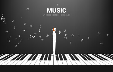 Vector silhouette of man standing with piano key with flying music note . Concept background piano music and recreation. © Panithan