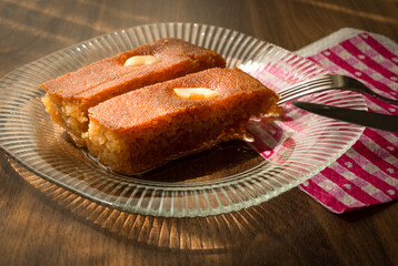 Turkish Dessert sambali, sambaba or sam tatlisi served in a plate with fork and knife on brown table.