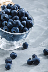 Blueberries on a black background, close-up, fresh berry in a bowl on a concrete background with a wrapped envelope with a berry. copies of space, delivery of berries.