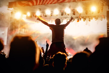 Man with raised hands opposite stage light. Night club party.