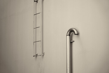 A fire stairs outdoors on a wall. Fire escape and ventilation pipe.