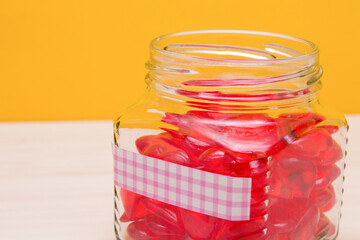 jar with hearts on the table, pink sticker on the jar, yellow background, charity and selfless help concept, copy place