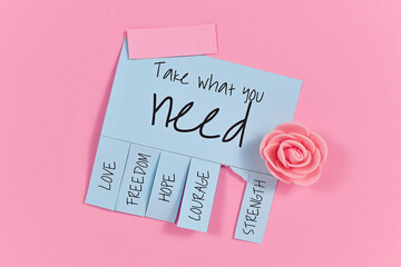 Blue tear-off stub note with text 'Take what you need' and words 'Love, Freedom, Hope, Courage' and 'Strength' on pink background