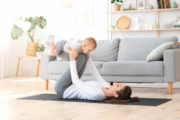 Healthy lifestyle. Young mom exercising at home with her infant baby